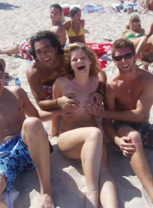 Nudist girl with three boys at the beach