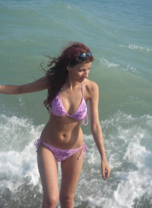 Brunette teen in yellow and red bikini laying on the sand