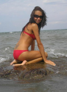 Blonde gf in black sunglasses and white bikini at the shore